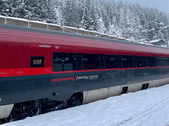 Austrian Railjet train arriving at a snow-covered platform in Bad Gastein — train travel in Europe