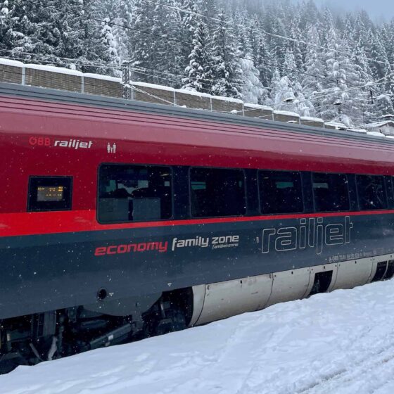 Austrian Railjet train arriving at a snow-covered platform in Bad Gastein — train travel in Europe